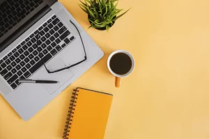 laptop, notepad, and coffee cup on desk